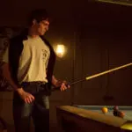 Man in T7C jeans playing pool in moody lighting
