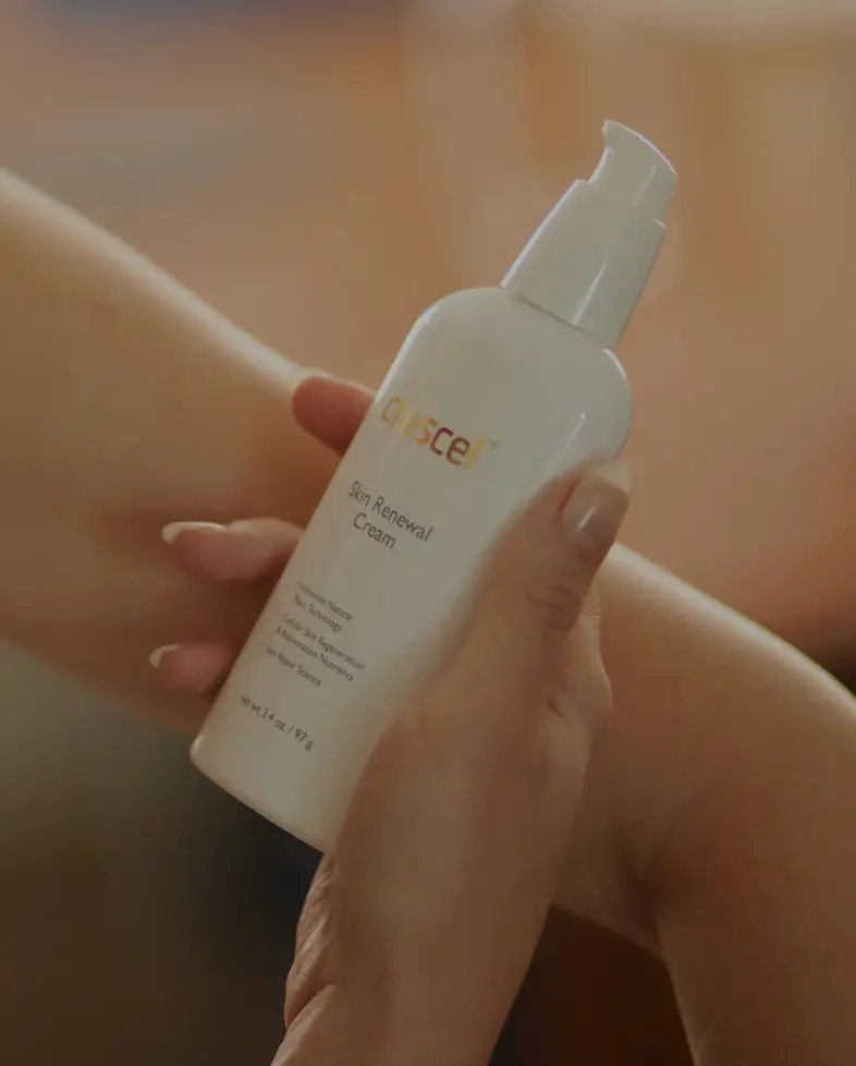 Hands applying Crescel Skin Renewal Cream during a product photo shoot.